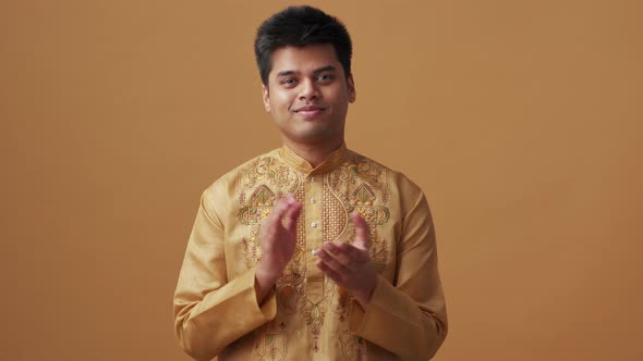 Confident Indian man in national cloth clapping hands