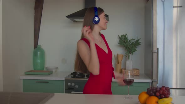 Carefree Girl in Headphones Enjoying Music in Kitchen