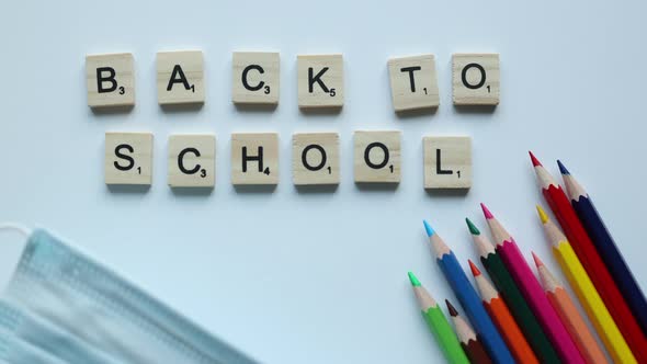 Back to School Written in Wooden Letters with Colorful Pencils and Medicine Mask on White Background