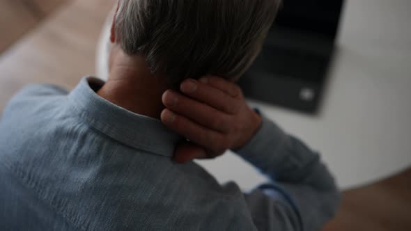 Closeup Back View of Unrecognizable Mature Grayhaired Male Experience Severe Pain in Neck Rubbing It