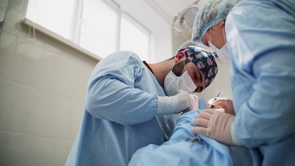 a male surgeon performs an operation