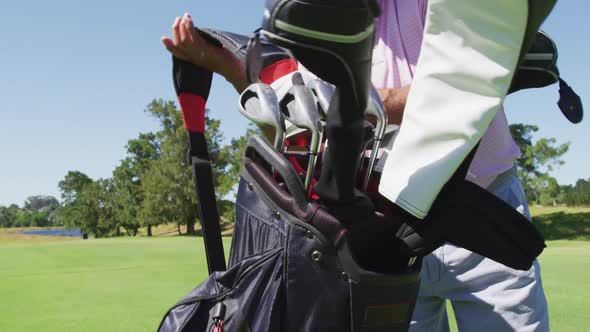 Caucasian senior man walking with his golf bag at golf course on a bright sunny day