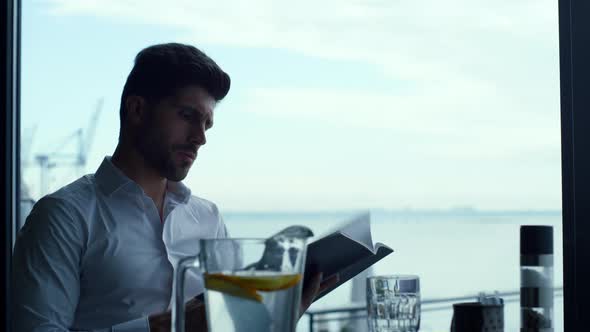 Relaxed Man Customer Reading Wine List in Panoramic Luxury Lounge Bar Portrait