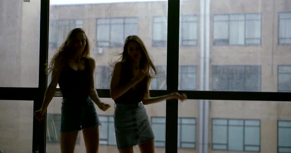 Women Silhouettes Dance Against Large Window and Building