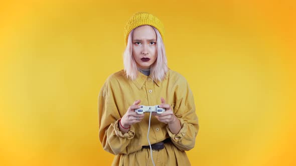 Pretty Young Girl Playing Video Exciting Game on Tv with Joystick on Yellow