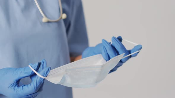 Video of biracial female doctor wearing face mask on blue background