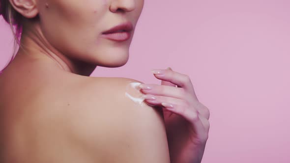 Woman Rubs Drop of Cosmetic Cream on Shoulder Closeup