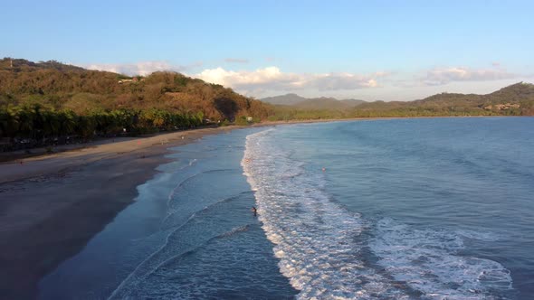 Beach in Costa Rica with surfers and tourists in the water. Waves rolling in. Province of Guanacaste