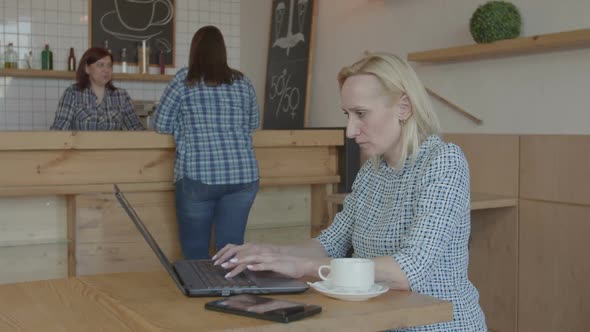 Pensive Female Blogger Working on Laptop in Cafe