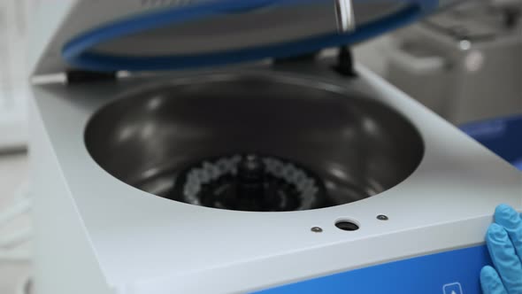 Female Lab Technician in Rubber Gloves Refills a Centrifuge and Closes It