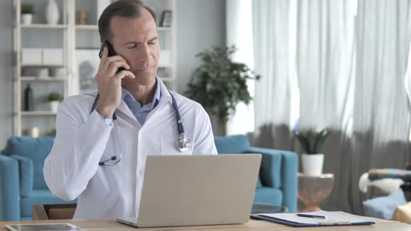 Senior Doctor Talking on Phone with Patient in Clinic