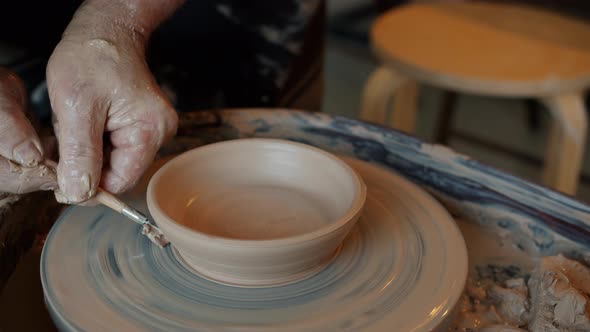 Experienced Potter Decorating Molded Bowl Using Professional Tools and Throwing Wheel