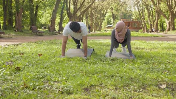 Young Muslim Man and Woman in Hijab and Activewear Standing in Plank Position at