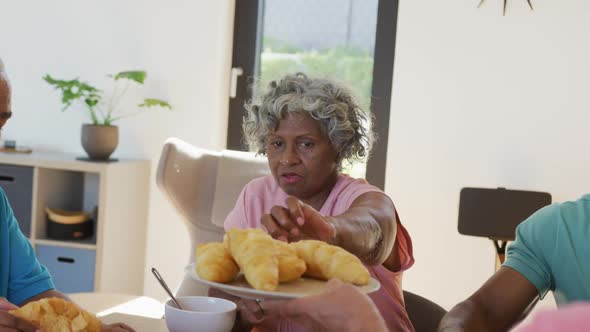 Happy senior diverse people having breakfast at retirement home