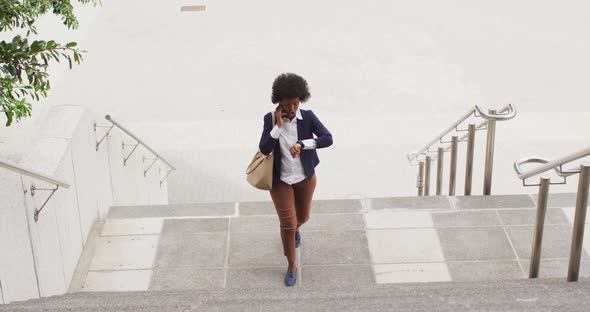 African american businesswoman walking and talking on smartphone