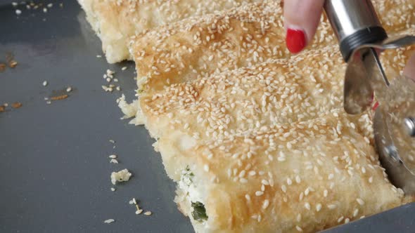 Filo pie with sesame cheese and spinach close-up 4K 2160p 30fps UHD footage - Cutting homemade baked