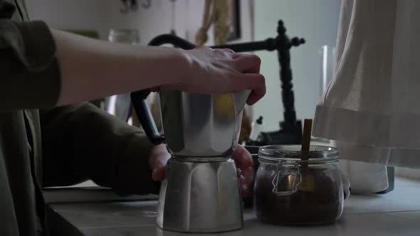 Woman make a coffee in moka pot in kitchen