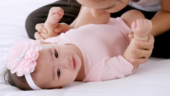 Young mother with her little baby playing on bed at home.