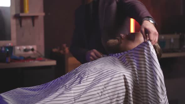 Handsome Man on a Barber's Chair Completes the Shaving Procedure