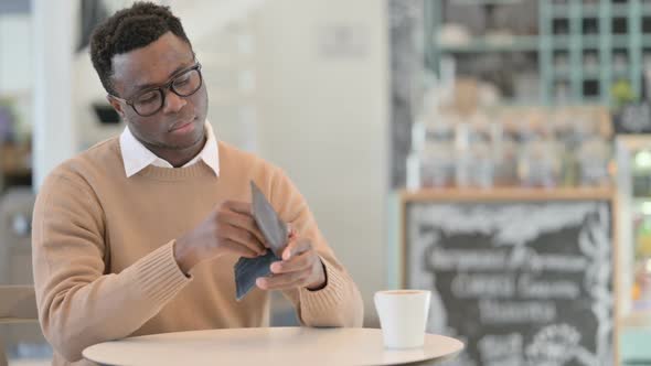 Creative African Man Checking Empty Wallet While Sitting in Cafe