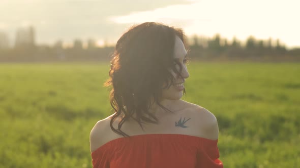 Portrait of a Beautiful Spanish Brunette Woman in a Red Dress at Sunset in a Wheat Field