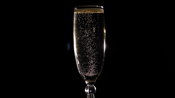 Closeup of a Glass of Champagne Slowly Spinning on a Black Background