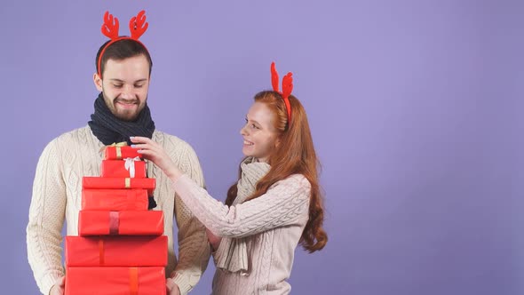 Happy Couple in Red Funny Horns with Christmas and New Year Gift at Studio