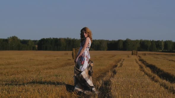 Redhead Woman with Plaid in Cage Runs Across Field Against Background of Hay