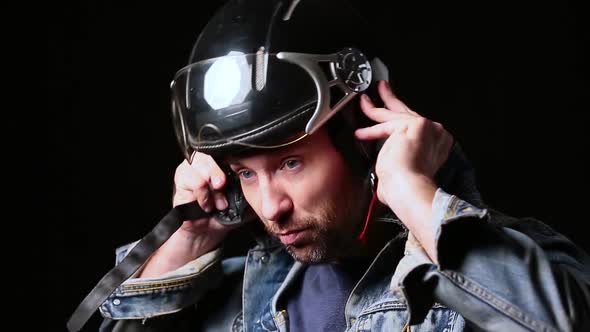 Blue Eyed Bearded Middle Aged Biker Taking on Helmet Over Dark Background.