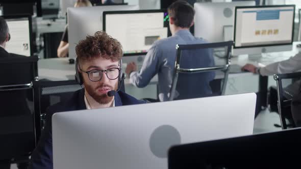 Close Up Portrait Man of a Technical Customer Support Specialist Talking on a Headset While Working