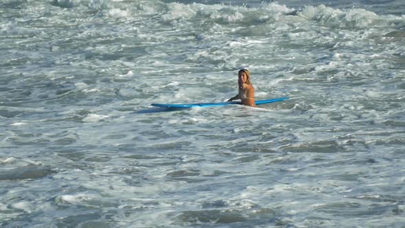 A young woman surfing in a bikini on a longboard surfboard.