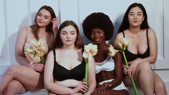 Four beautiful women holding flowers, smiling at camera