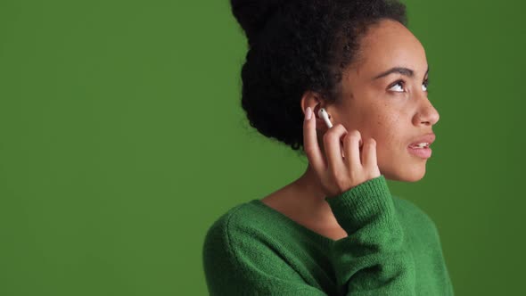 African woman in green shirt listening music in headphones