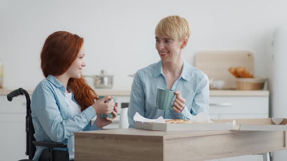 Little Girl with Disability Eating Pizza and Tea with Mother at Home and Talking Discussing Future