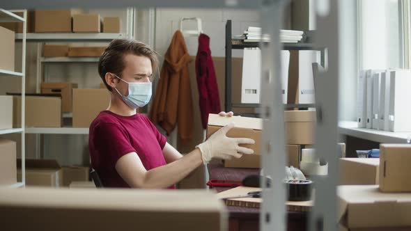 Man Employee of Warehouse Wearing Medical Mask and Protective Gloves Taking Photo of Delivery Box on