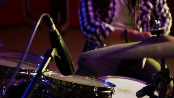 Man with dreadlocks playing drums in a music studio