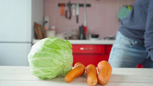 Man Puts Fresh Vegetables on Wooden Table on Kitchen