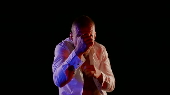 a Man in an Unbuttoned White Shirt is Boxing on a Dark Background