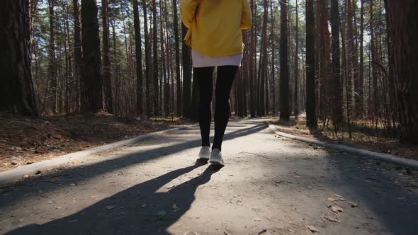 Rear view of an active sportswoman running in a city park, fashionable sports leggings, sneakers.