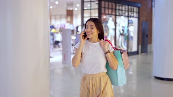 Woman Talking on Mobile Phone with Friend During Shopping Day in Mall