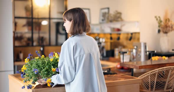 Housewife Decorating Interior with Flowers in the Kitchen