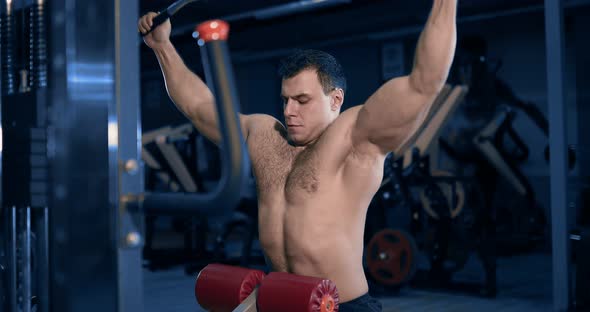 Bodybuilder Doing Exercise on the Simulator in the Gym