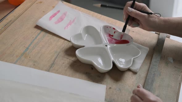 Hand of Senior Artist Diluting Paint on an Easel