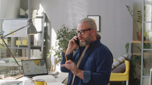 Senior Man Talking on Mobile Phone in Office