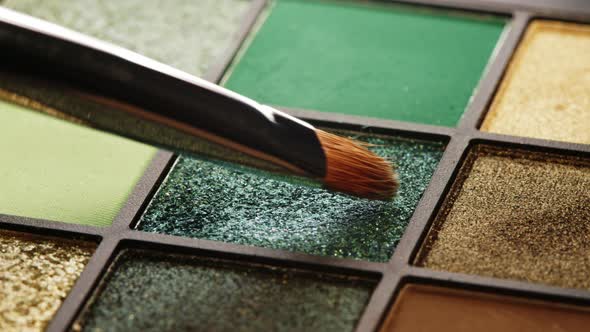 Brush Gains Green Pigment on Pile To Be Used in Make-up. Artist Working with Eyeshadows Palette