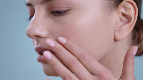 Close Up of Pretty Woman Touching Face with One Hand While Looking to Camera and Smiling 