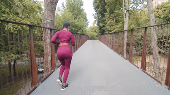 Black Fitness Woman in Activewear Running on Bridge Outdoor During Everyday Morning Workout