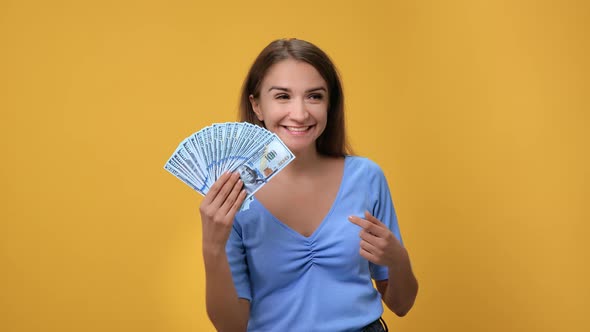 Portrait Happy Rich Woman Waving Cash Dollar Money Fan Posing Isolated on Orange Studio