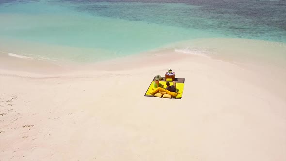 Aerial drone view of a man and woman couple having a picnic meal on a tropical island beach