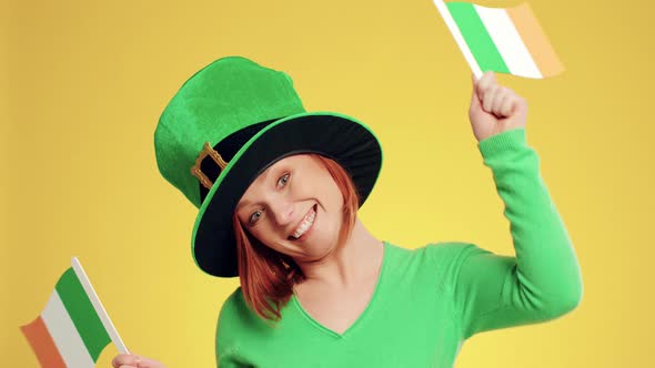 Playful woman with leprechaun's hat and Irish flags dancing